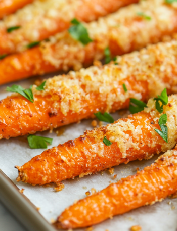 A plate of crispy Parmesan-coated roasted carrots, garnished with fresh herbs. The rich seasoning and melted cheese create a flavorful, crunchy exterior, making them a delicious and visually appealing side dish.