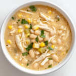 A large pot of creamy white chicken chili simmering on the stove, filled with tender shredded chicken, beans, corn, and a blend of spices.