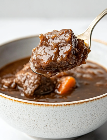 This image shows the Ninja Foodi pot filled with browned beef, ale, chopped onions, carrots, and celery, ready to slow cook into a rich and hearty stew."