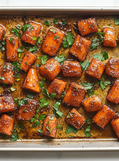 This image shows freshly chopped carrots on a parchment-lined baking sheet, ready to be coated with a buttery, sweet, and savory seasoning before roasting."